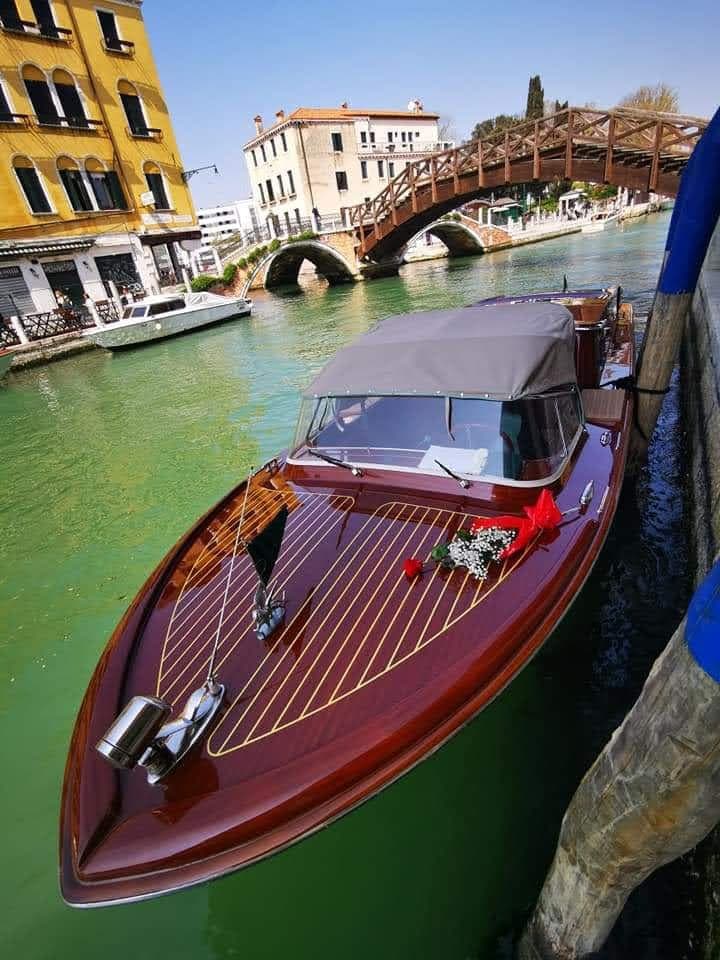 Riva classic boat in Venice canal with roses